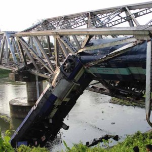Assam: A passenger train hangs from a bridge after it derailed at Basugaon near Kokrajhar -Chirang district border of Assam on May 23, 2015. (Photo: IANS)