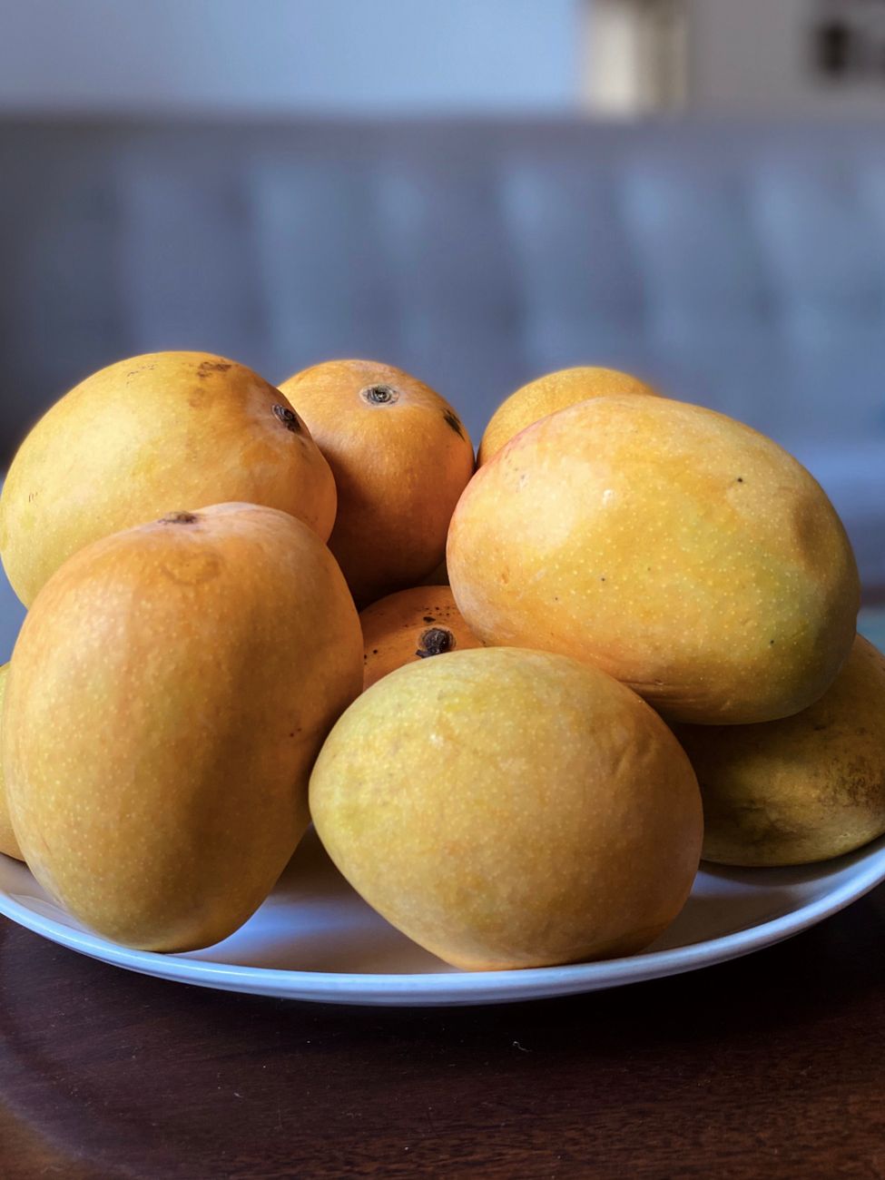 ripe yellow mangoes on white ceramic plate.