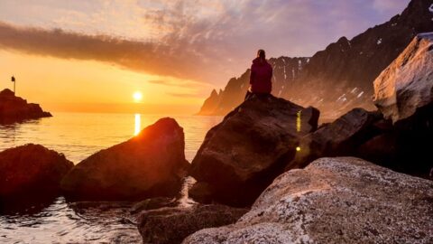 person sitting on rock formation beside body of water European