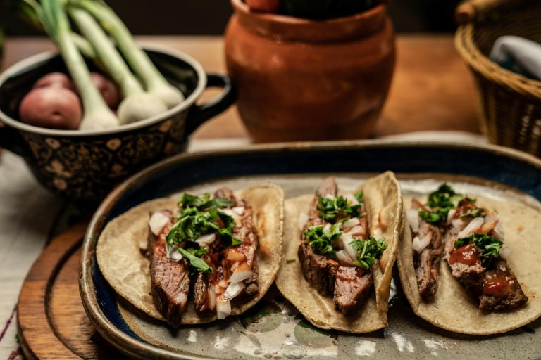 sliced beef steak and green vegetable on top of tortilla