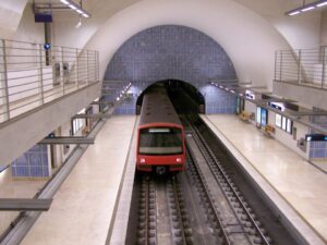 Lisbon metro station with azulejo tile mural and a woman carrying a matching canvas tote, evoking Lisbon Metro Stillness.”
