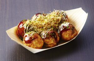 Takoyaki Japanese street food – freshly grilled octopus balls topped with bonito flakes, mayonnaise, and green onions served in Osaka.