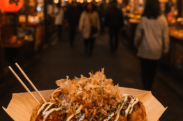 Tokyo street food scene with takoyaki, skewers, and neon-lit stalls”