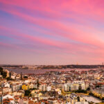 treet food stalls and kiosks in Lisbon’s Alfama district, with locals enjoying snacks during a festival.