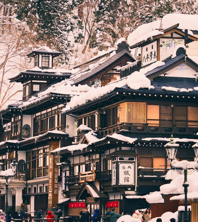 Traditional Japanese onsen in Yamagata during winter, with snow-covered rooftops and wooden architecture evoking quiet rituals.”