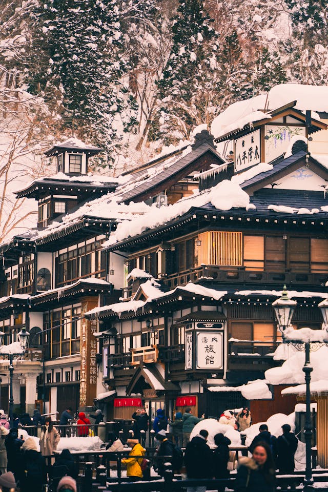 Traditional Japanese onsen in Yamagata during winter, with snow-covered rooftops and wooden architecture evoking quiet rituals.”
