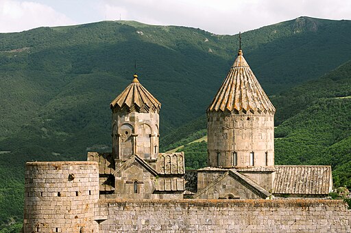 Tatev Monastery in Armenia perched on a cliff with mountains in the background