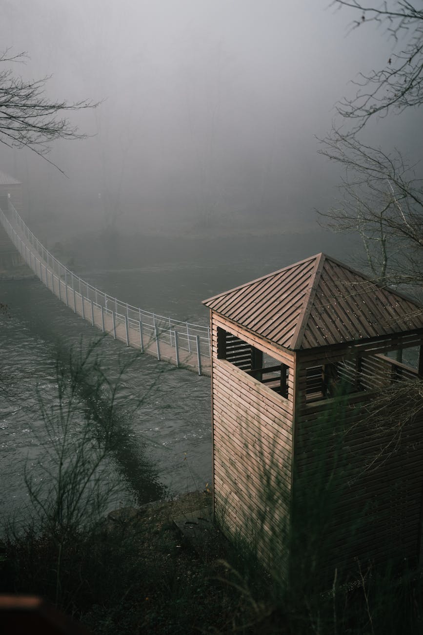 foggy suspension bridge in bouillon forest. A foggy suspension bridge in the Bouillon forest, fading into mist and evoking a quiet borderlands travel reflection through a soft, in‑between landscape