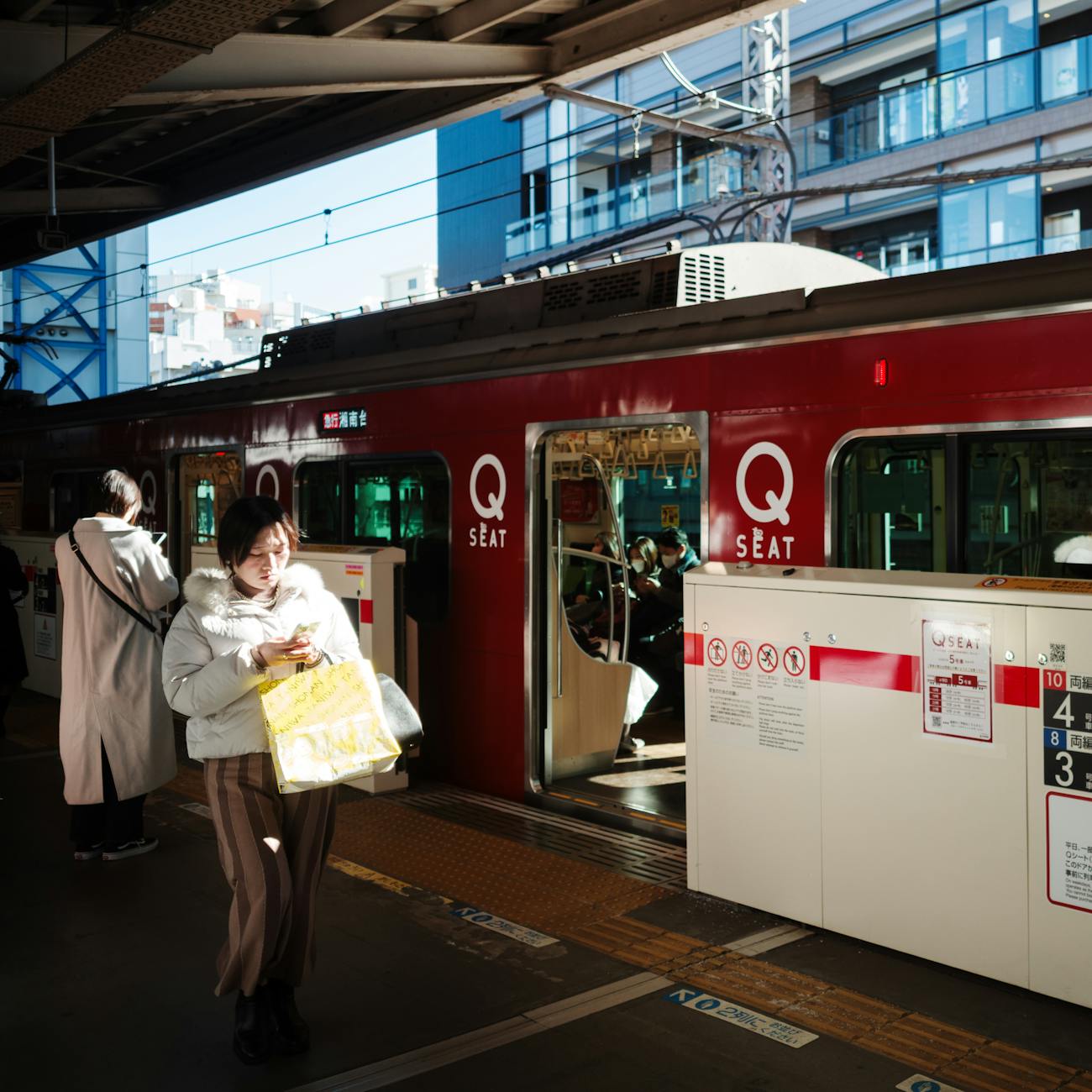 A moment between stations, where the city softens and the journey begins.. Commuters at Tokyo train station platform. Poetry of transit