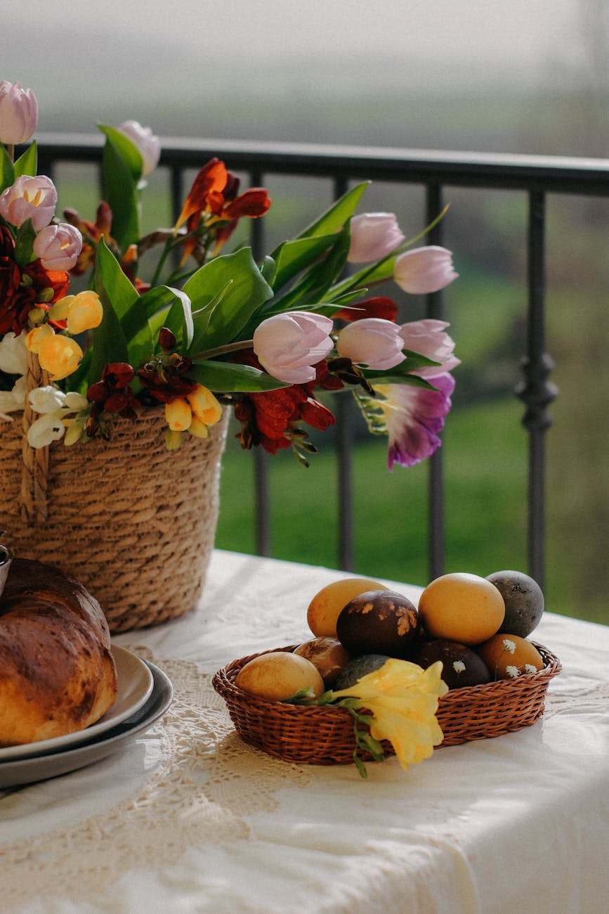 a basket with colorful Easter eggs and flowers standing on a table