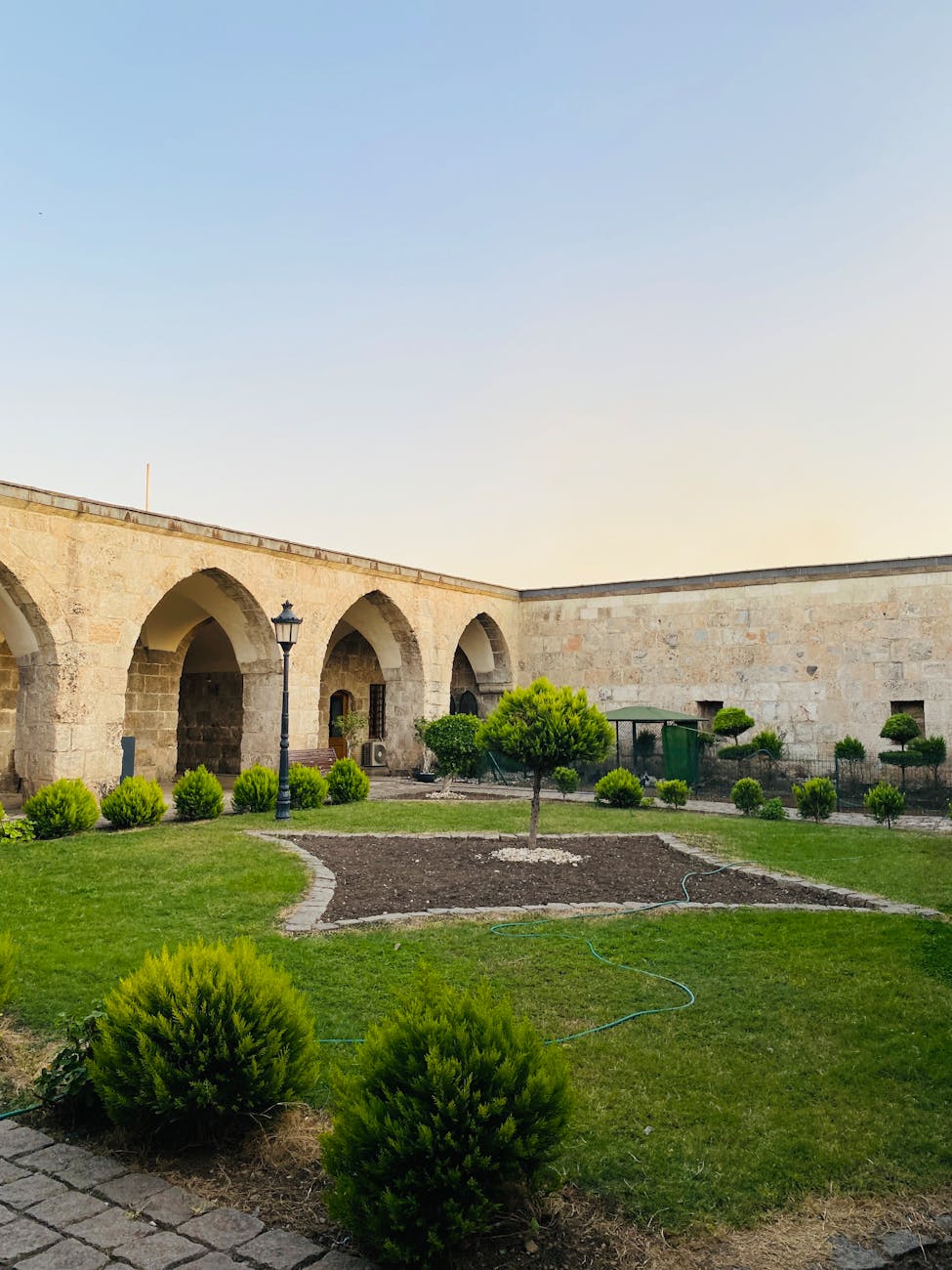 historic courtyard with arched stone walls. Historic Sheki caravanserai courtyard with arched stone walls and soft filtered light.