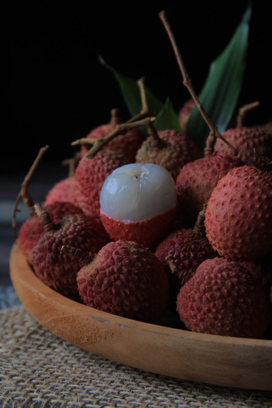 close up photo of lychees on wooden plate. litchi fruit early summer freshness