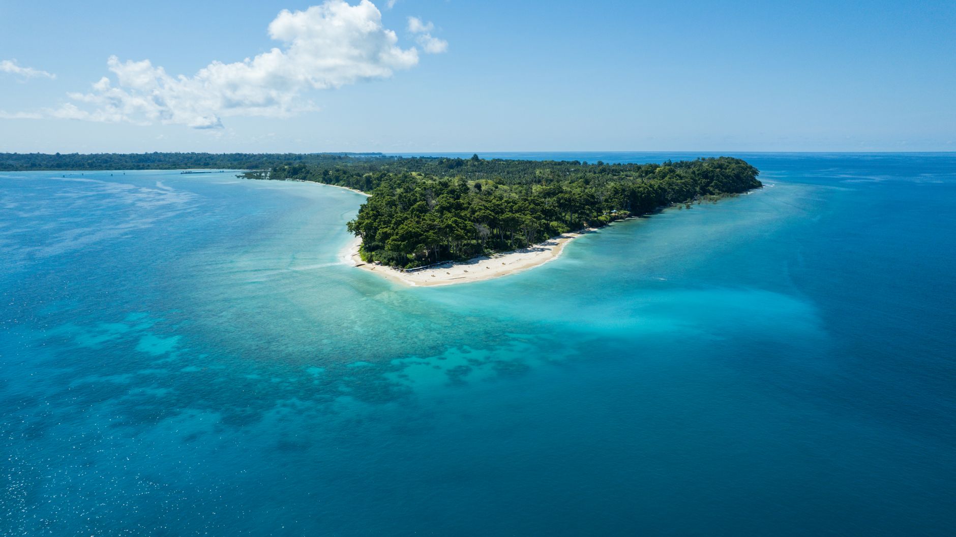 drone shot of the neil island. Aerial view of Neil Island’s turquoise shallows and reef edges under soft, diffused monsoon light.
