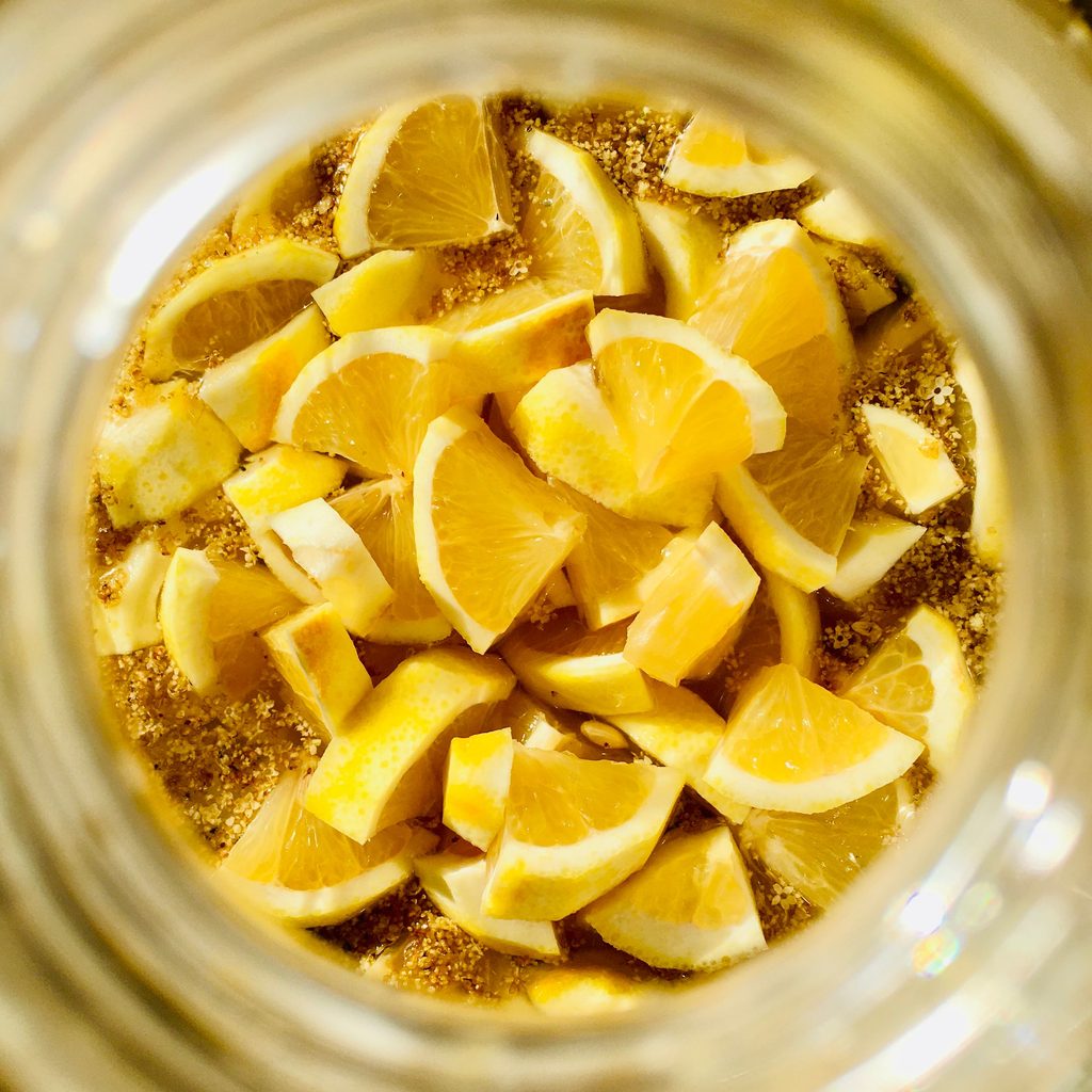 Top‑view of sliced lemons preserved in a jar, showing the bright citrus note that balances warm Moroccan spices.