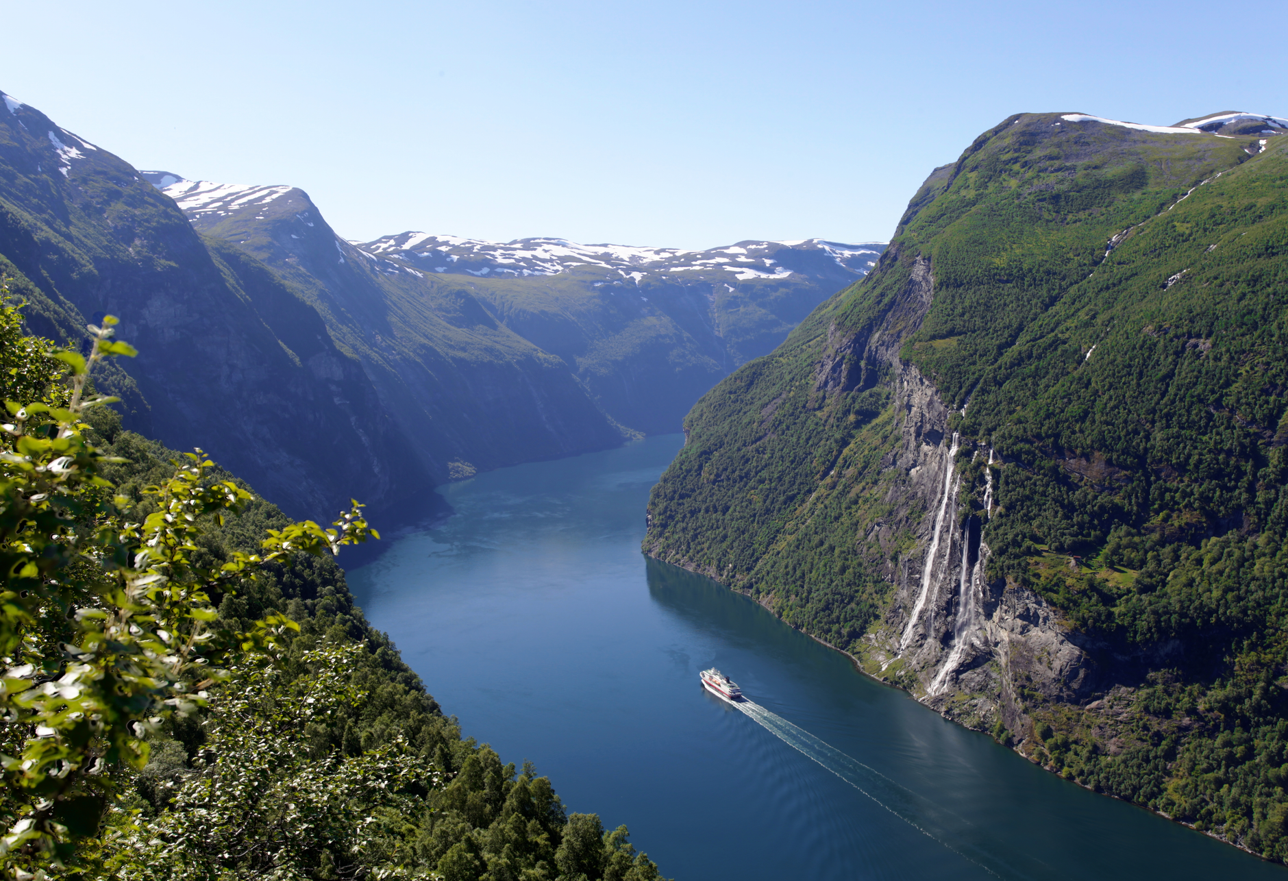 geirangerfjord wasserfall. A dramatic view of Geirangerfjord with steep mountains, misty blue water and a cascading waterfall, capturing Norway’s quiet autumn stillness and fjord serenity.