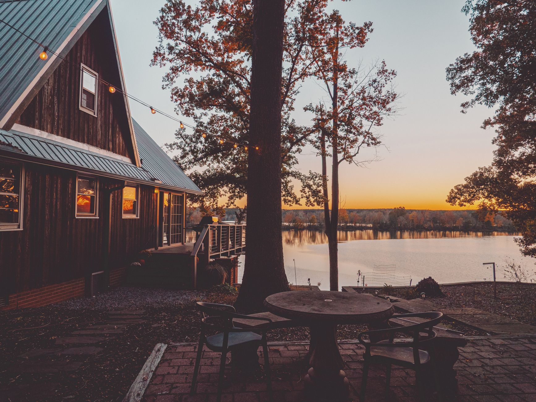 cozy lakeside house at sunset with fairy lights